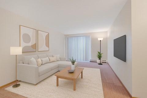 A living room with a white couch, a wooden coffee table, and a flat screen TV mounted on the wall.
