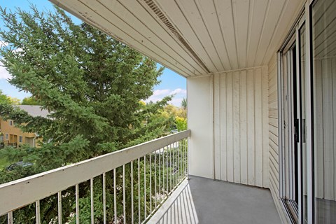 A private balcony here at Gateway Gardens featuring a covered outdoor space with railing views of mature trees and a quiet neighborhood setting, offering a peaceful spot to enjoy fresh air.