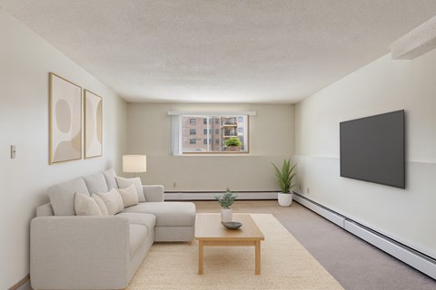 A living room with a grey couch, a wooden coffee table, and a flat screen TV mounted on the wall.