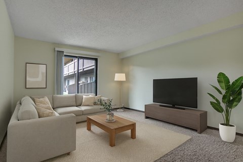 A living room with a white couch, a wooden coffee table, a flat screen TV, and a potted plant.