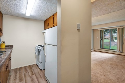 A kitchen with a white refrigerator and wooden cabinets.