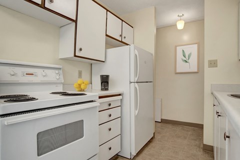 A white stove and refrigerator in a kitchen with a painting hanging on the wall.