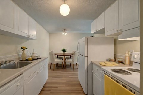 A kitchen with white cabinets and a table with chairs.