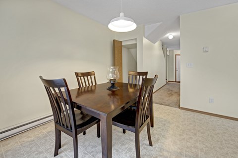 A dining room with a wooden table and chairs.