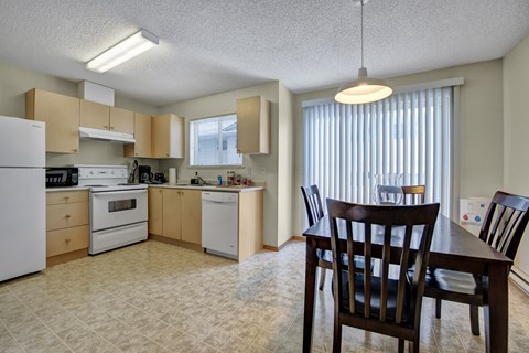 A kitchen with a table and chairs.