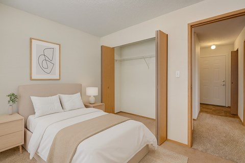 A bedroom with a bed, nightstand, and a framed picture on the wall.