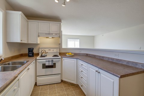 A kitchen with white cabinets and a stove top oven.