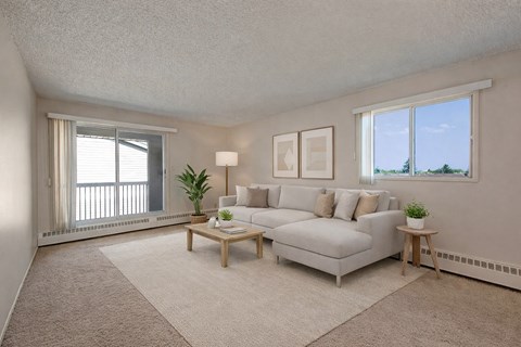 A living room with a white couch, a coffee table, and two potted plants.