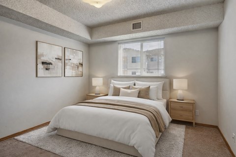 A bedroom with a large bed and two nightstands with lamps.
