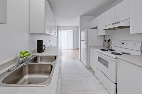 A kitchen with white appliances and a stainless steel sink.