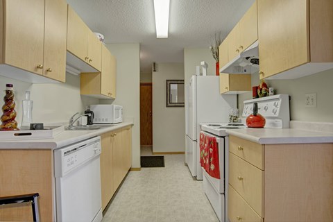 A kitchen with white appliances and wooden cabinets.