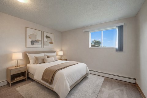 A bedroom with a large bed and two lamps.