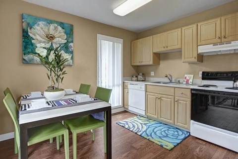 A kitchen with a table and chairs and a flower painting on the wall.