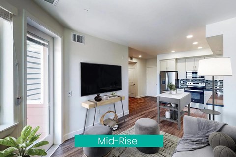 A modern living room with a flat screen TV and a kitchen in the background.