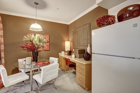 A kitchen with a table and chairs and a fridge.