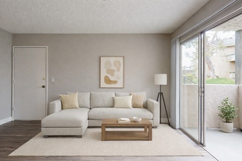 A living room with a white couch and a painting on the wall.