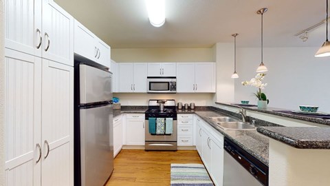 A modern kitchen with white cabinets and a granite countertop.