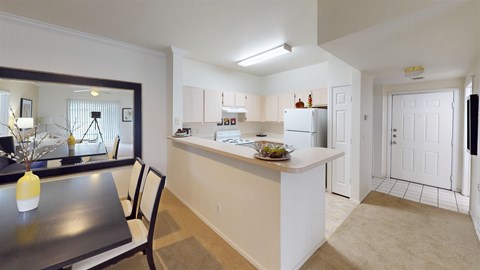 An open kitchen and dining area here at Camelback Pointe featuring light cabinetry, a breakfast bar, a white refrigerator, a dining table with chairs, and a bright entry with tile flooring.