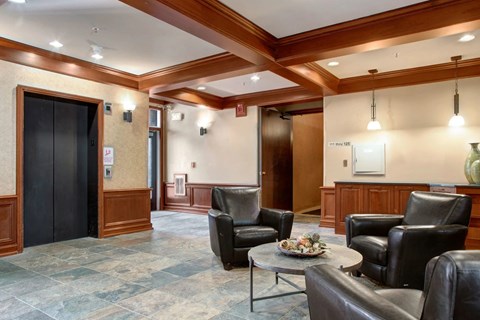 A living room with a black leather couch and a coffee table.