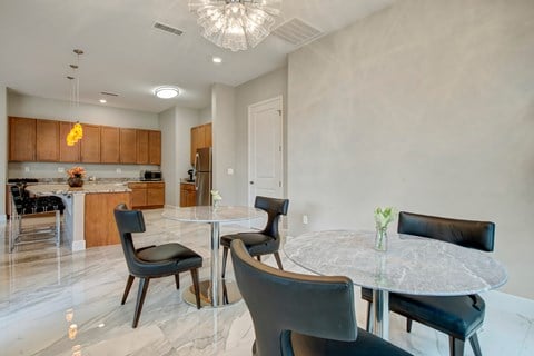 A modern dining room with a glass table and black chairs.