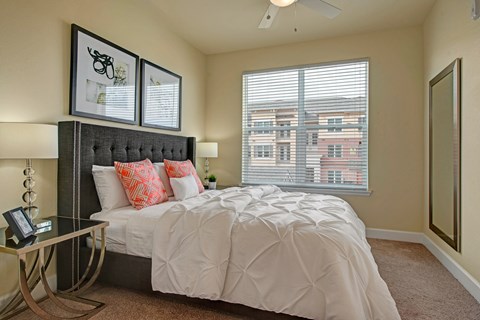 A bedroom with a large bed and a window with blinds.