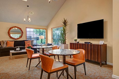 A living room with a round mirror, a fireplace, a dining table with chairs, and a television.
