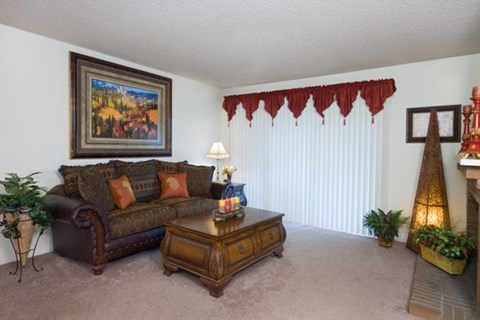 A living room with a brown couch, a coffee table, and a painting on the wall.