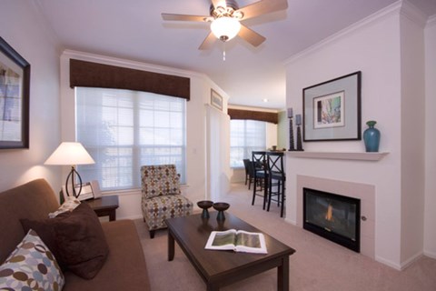 A living room with a brown couch, a fireplace, and a ceiling fan.