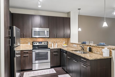 A modern kitchen with dark brown cabinets and stainless steel appliances.