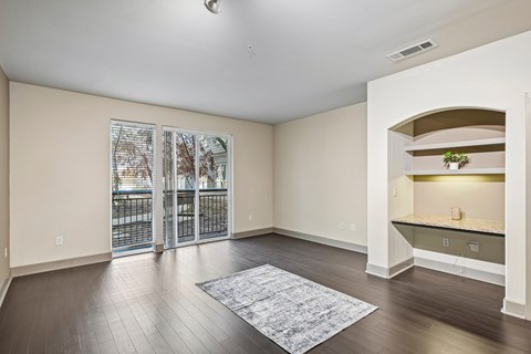 A spacious room with a sliding glass door and a rug on the floor.