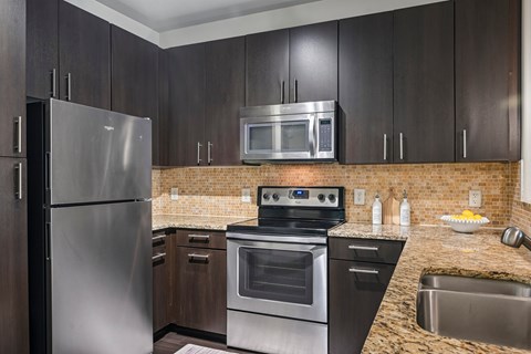 A kitchen with a stainless steel refrigerator, oven, and microwave.