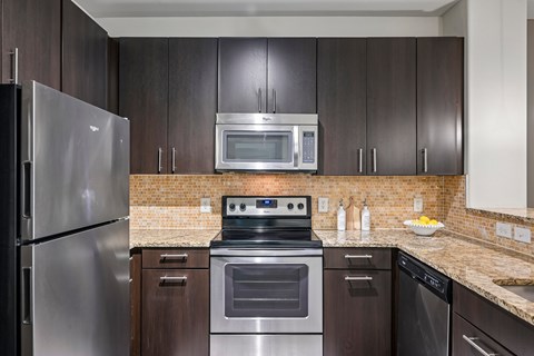 A modern kitchen with dark wood cabinets and stainless steel appliances.