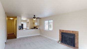 a living room with a fireplace and a kitchen in the background