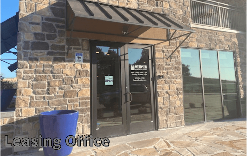 Stone building exterior with a glass door labeled "Weidner" and "Leasing Office." A blue planter sits nearby, and the scene appears sunny and welcoming.