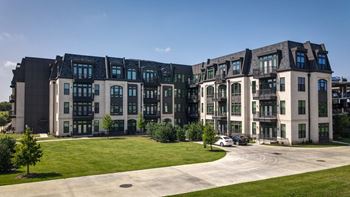 a row of apartment buildings with green grass and a sidewalk