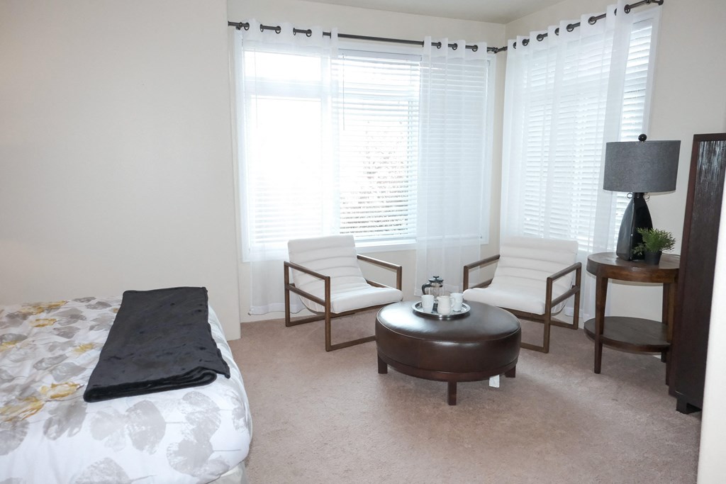 a bedroom with a bed and two chairs and a table