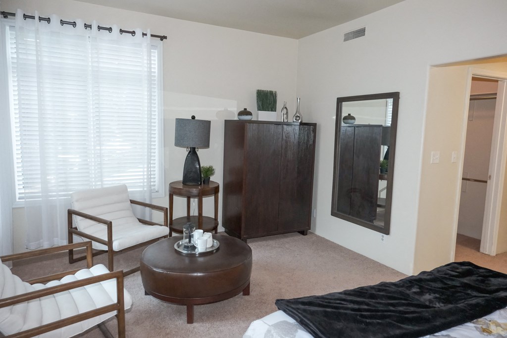 a living room with a bed and a dresser and a mirror