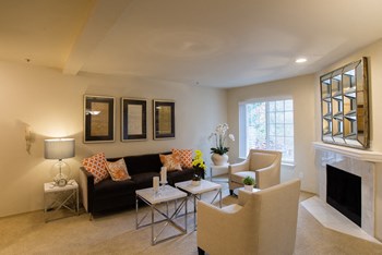 A spacious living room with a large window and fireplace Windsong Living Room - Photo Gallery 5