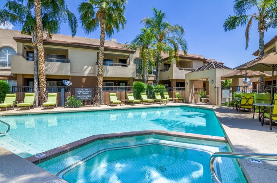 a resort style pool with lounge chairs and umbrellas in front of a building
