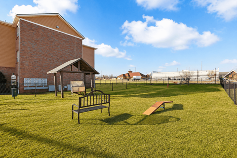 A park with a bench and a playground in the background.
