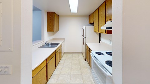 A kitchen with a stove, sink, and cabinets.
