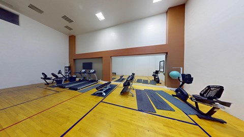 A gym with a yellow floor and exercise equipment.