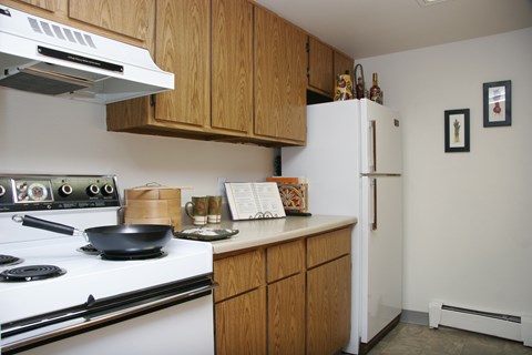A kitchen with a white stove and wooden cabinets.