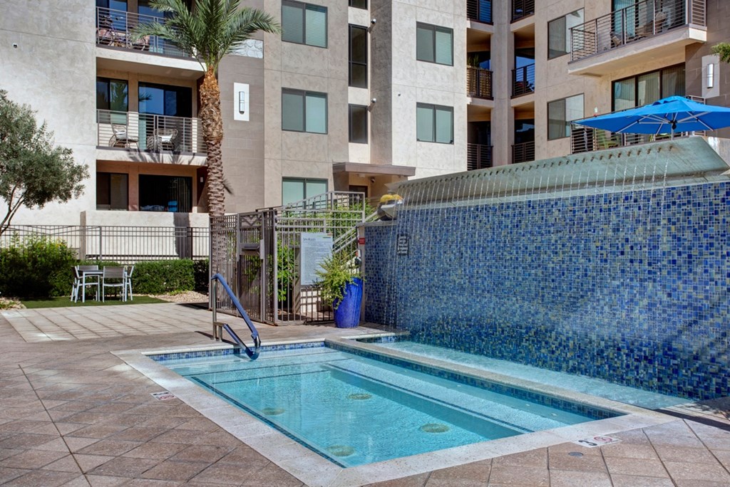 a swimming pool with a waterfall in front of an apartment building