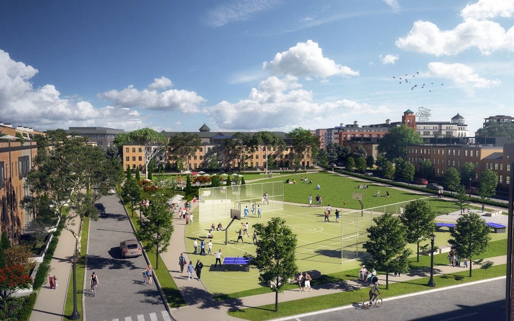 A vibrant community park near The Collection at Highland Bridge Apartment Homes on a sunny day features a sports court with people playing and relaxing. Surrounded by trees, buildings, and a blue sky.