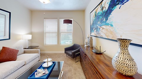 A living room with a white sofa, a coffee table, and a large painting on the wall.