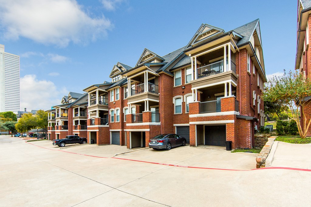 an empty parking lot in front of a brick apartment building