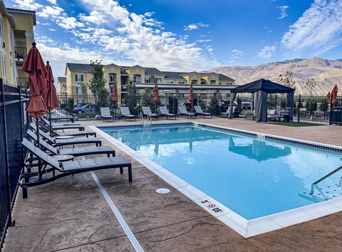 A pool with sun loungers and a mountain in the background.