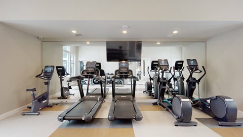 A spacious gym with treadmills, elliptical machines, and stationary bikes.