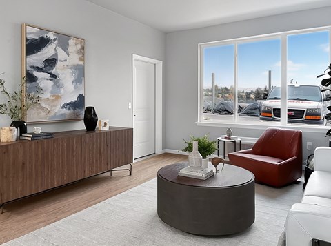 A living room with a brown sofa, a red chair, a grey coffee table and a painting on the wall.